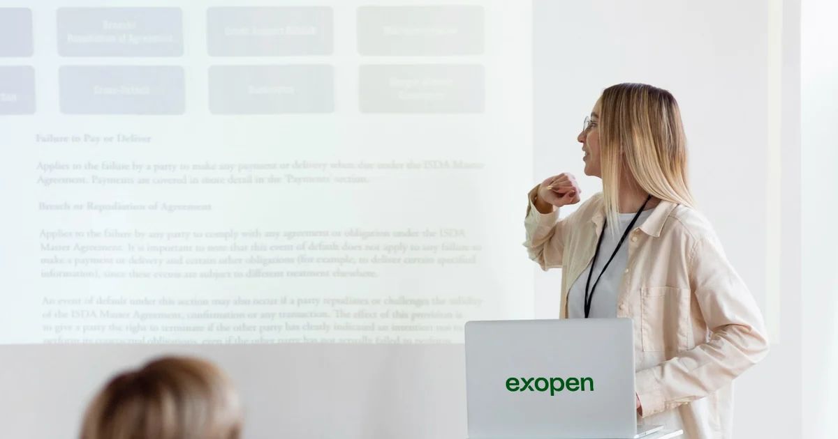 A woman presents beside an Exopen laptop to colleagues in a meeting room.
